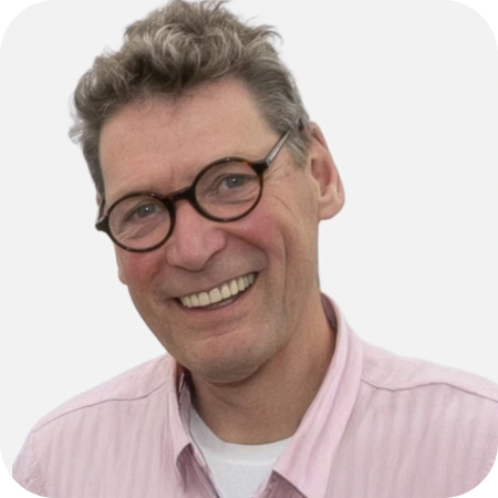 Professional headshot of a smiling male IT team member wearing glasses and a light pink shirt against a clean white background.