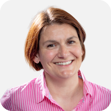 Professional headshot of a smiling female IT team member wearing a pink striped shirt against a clean white background.