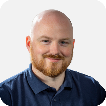 Professional headshot of a male IT team member wearing a navy polo shirt against a clean white background.