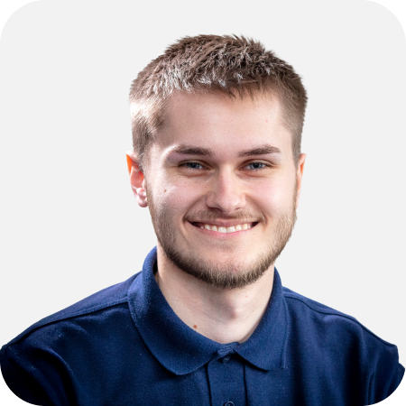 Professional headshot of a smiling male IT support team member wearing a navy polo shirt against a clean white background.